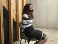 Woman in skirt and heels taped to chair